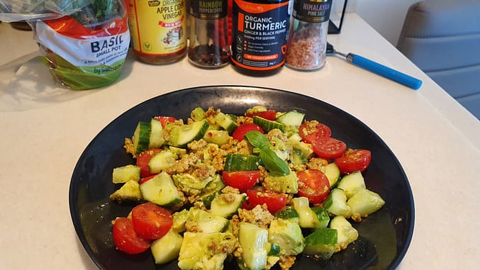 A healthy plate example - cucumber, tomato, avocado, fresh basil, extra virgin olive oil, lemon, organic pork with turmeric fried in grass-fed butter.